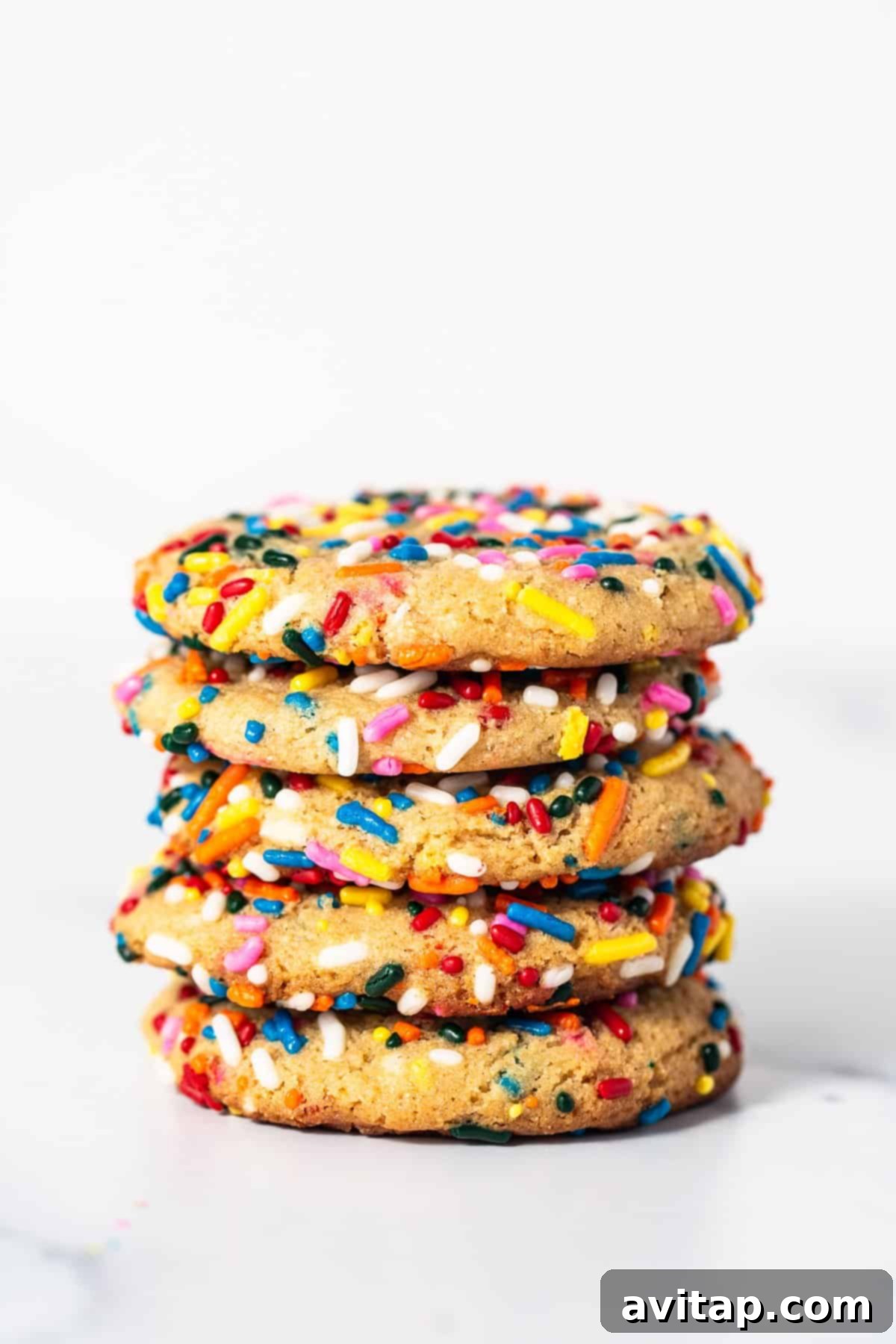 A close-up shot of several masa cookies stacked together, showing their textured surface and colorful sprinkles.