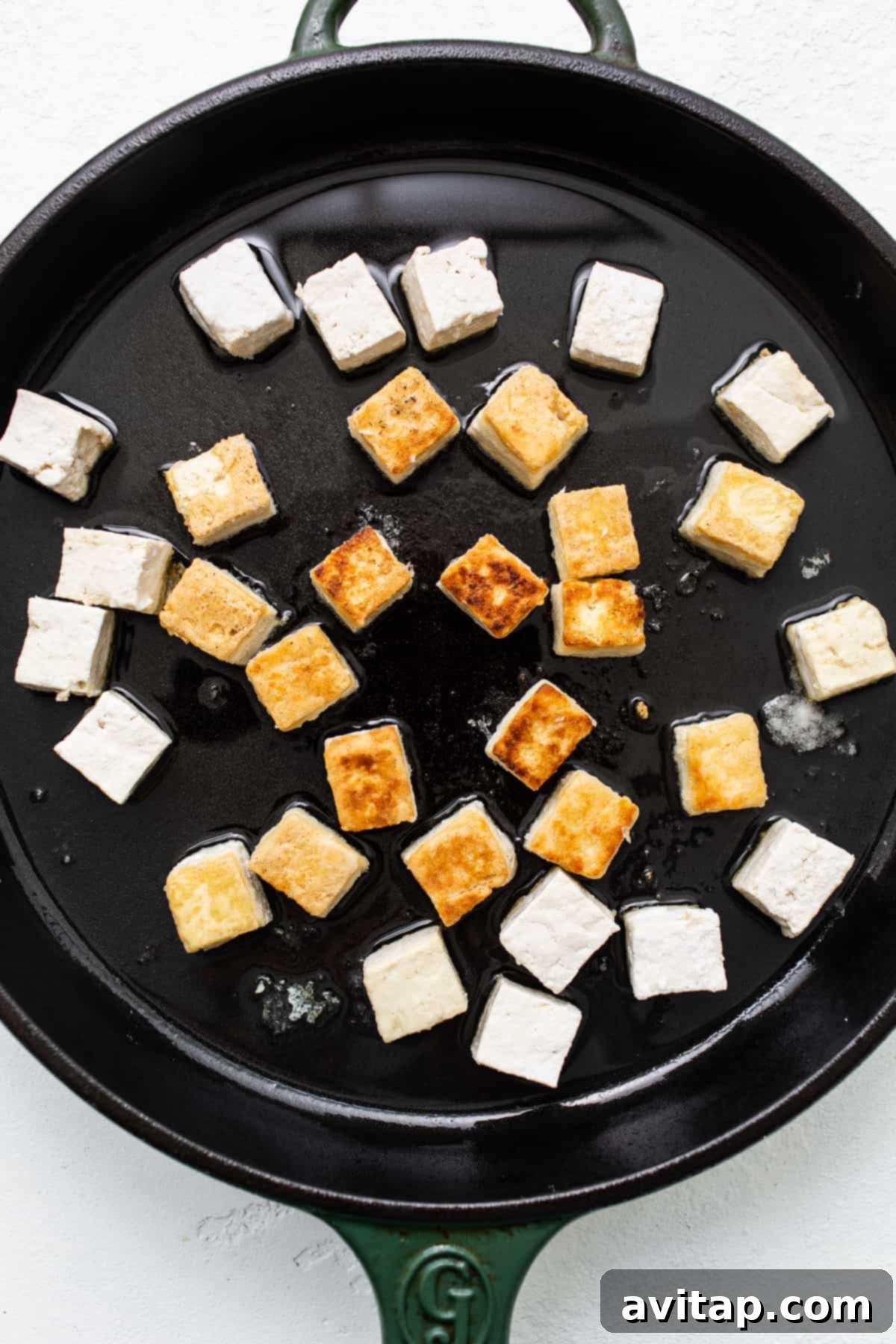 Crispy tofu frying in hot oil in a skillet.
