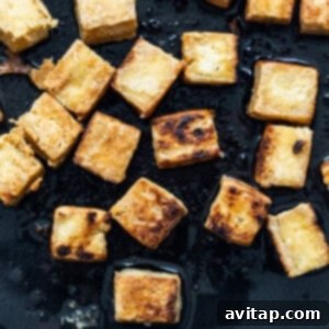 Cooking tofu in a pan, showing the golden-brown crisp.