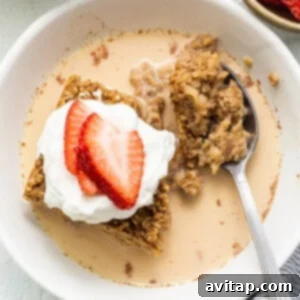 Tres leches baked oatmeal in a bowl, soaked with sauce and topped with fresh fruit, ready to eat.