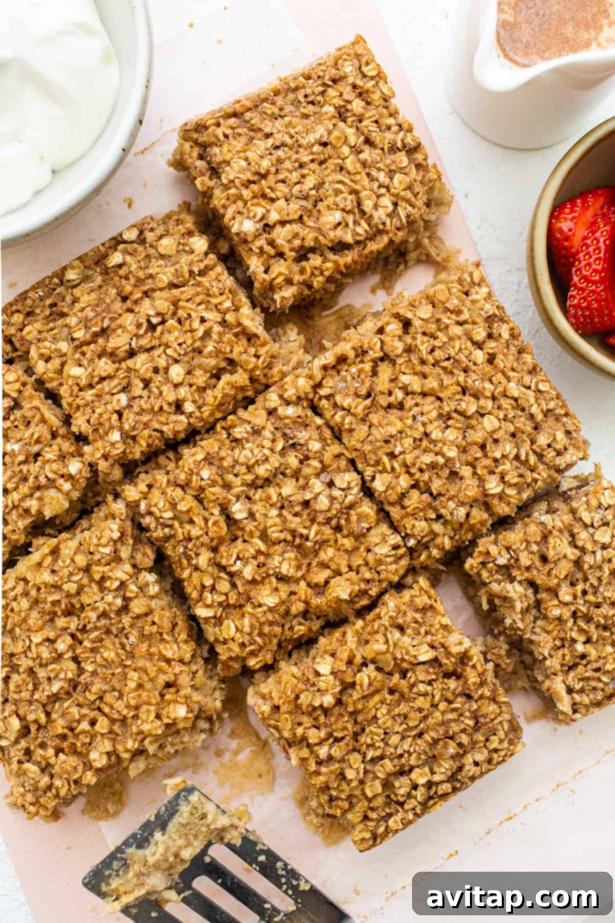 Perfectly portioned squares of golden-brown tres leches baked oatmeal elegantly arranged on a rustic wooden cutting board, signaling they are ready to be served and enjoyed.
