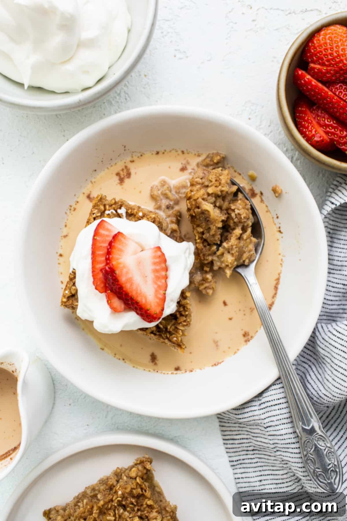 A comforting bowl of Tres Leches Baked Oatmeal, lovingly drizzled with the three-milk sauce and generously topped with an assortment of fresh berries, poised to be savored.