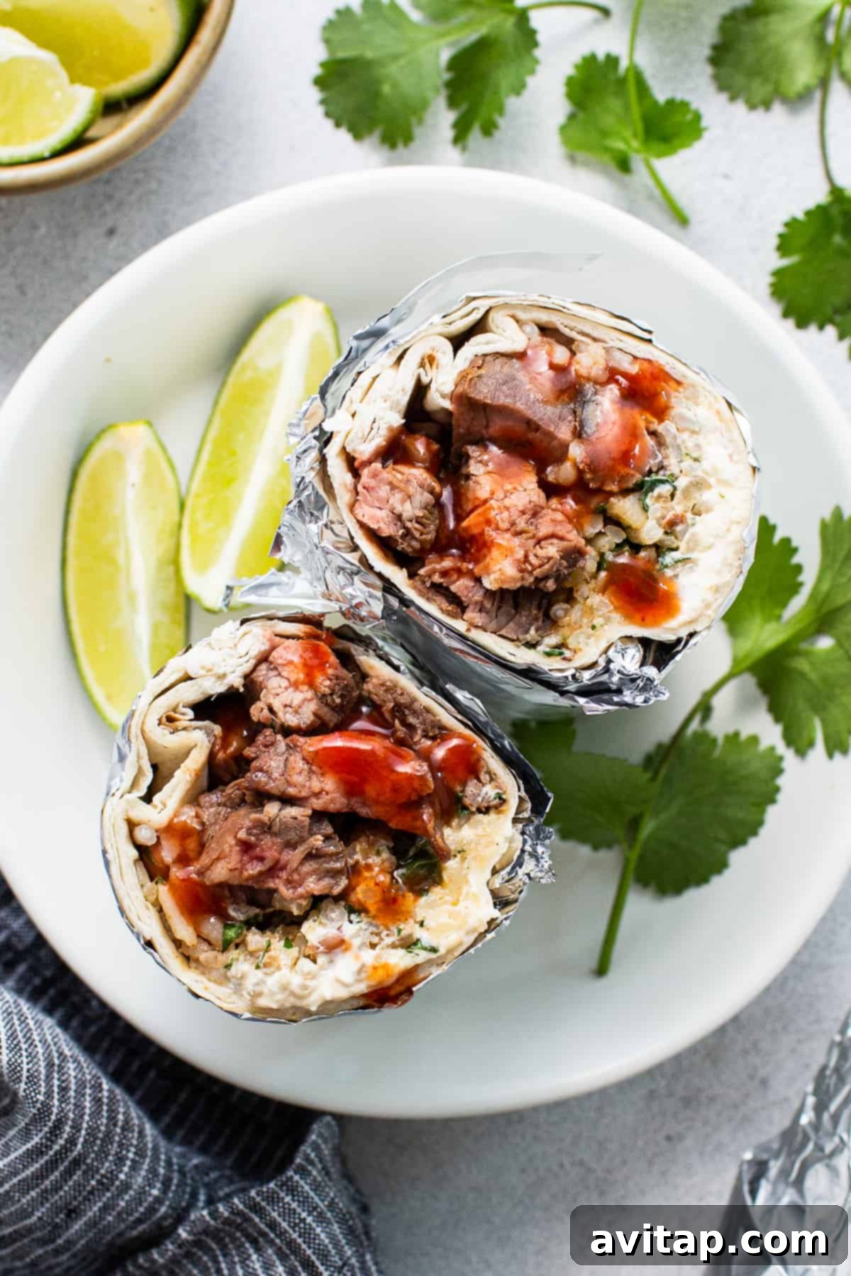A generously sized steak burrito, neatly wrapped in foil and placed on a rustic wooden plate, hinting at a delicious and satisfying meal perfect for lunch or dinner.