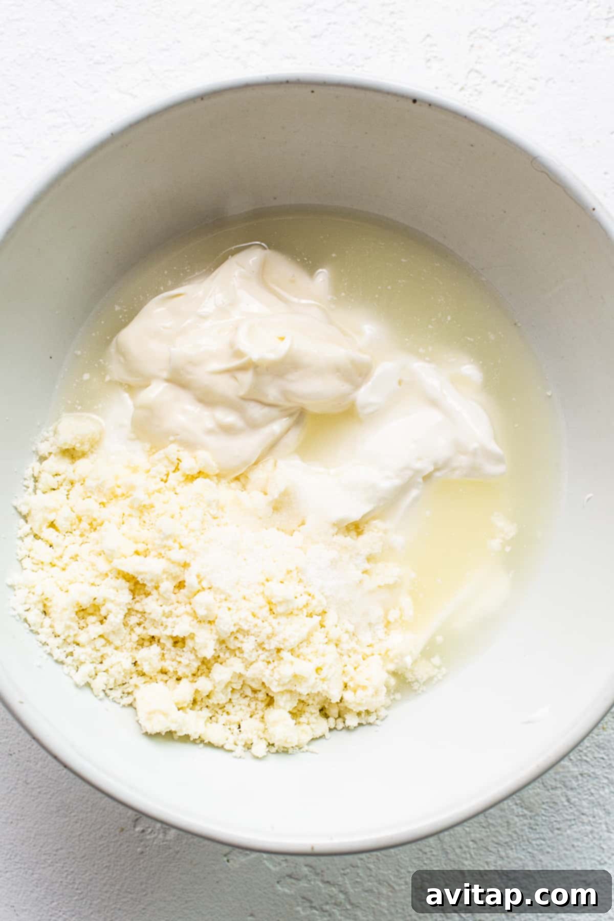 A ceramic bowl filled with creamy, off-white cotija cheese sauce, garnished with a sprinkle of fresh cilantro, showcasing its rich texture and appetizing appearance.