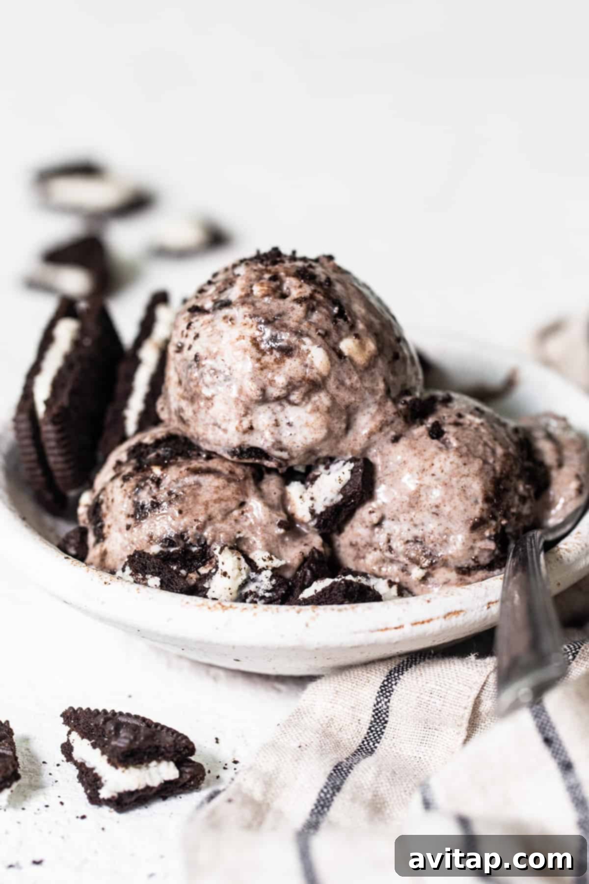 A bowl filled with three generous scoops of creamy cookies and cream cottage cheese ice cream, garnished with crumbled Oreo pieces, ready to be enjoyed as a protein-packed dessert.