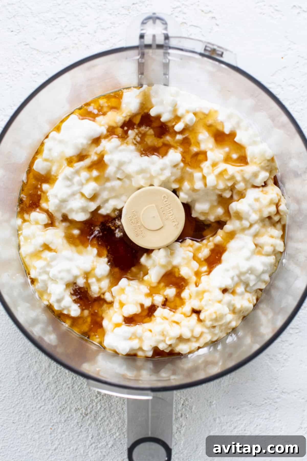 Close-up shot of creamy cottage cheese being processed in a high-speed food processor, indicating the first step in making the protein-packed ice cream.