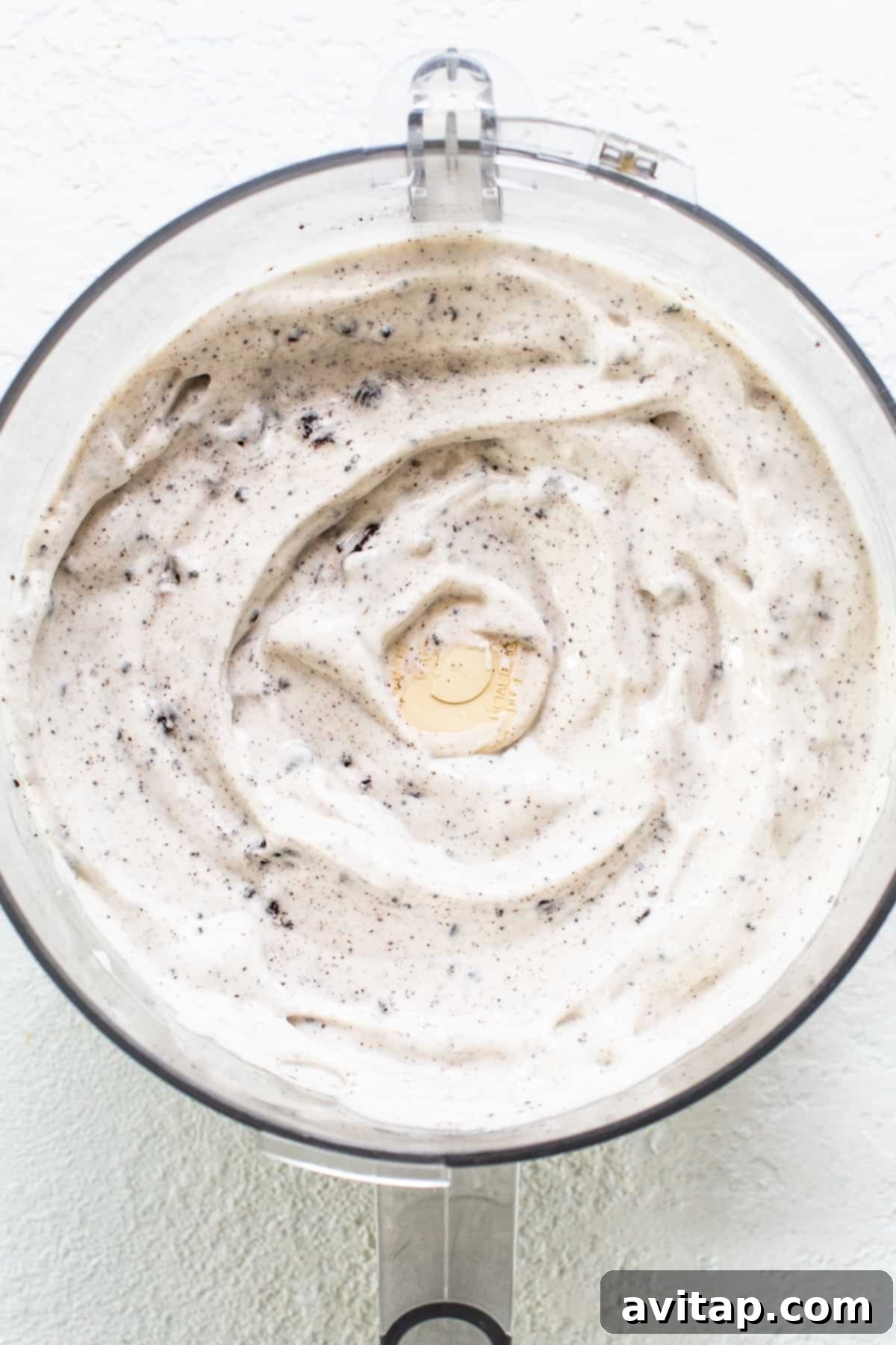 The smooth, blended cottage cheese ice cream base with cookie chunks visible in a food processor, ready for freezing.