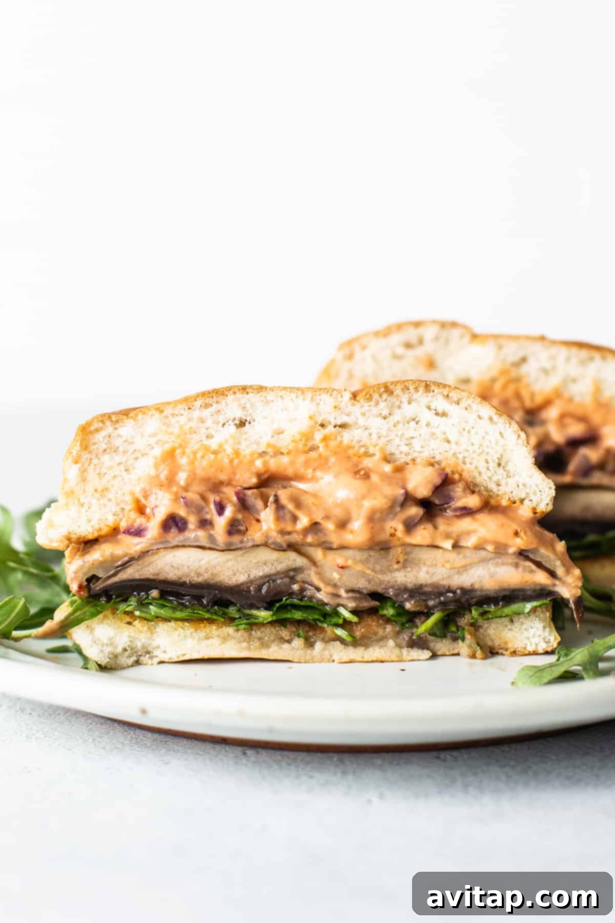 A perfectly grilled portobello mushroom burger, topped with melted cheese, fresh red onion, and vibrant greens, served on a toasted bun.