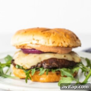 A fully assembled portobello mushroom burger on a plate, ready to be eaten.