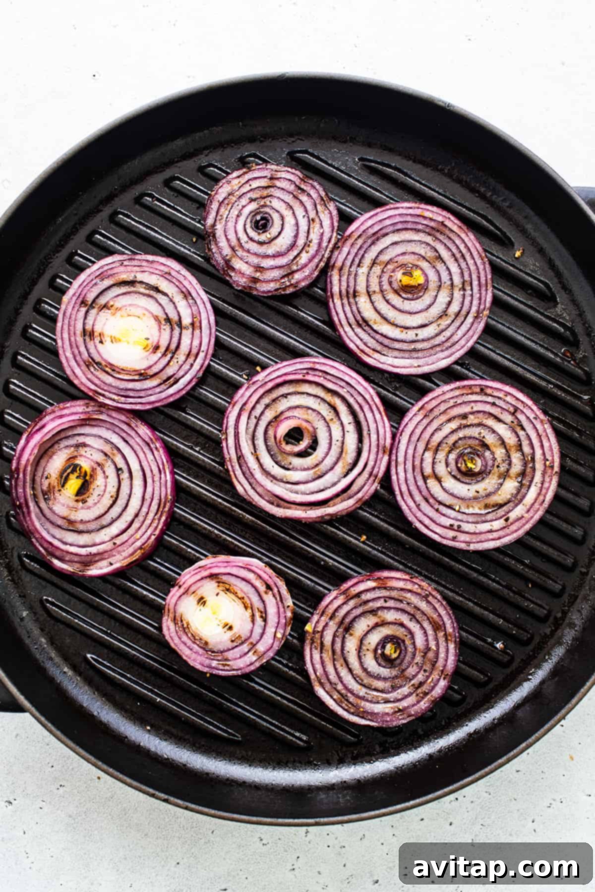 Perfectly grilled red onion slices arranged on a grill pan, showcasing their tender texture and slight char.