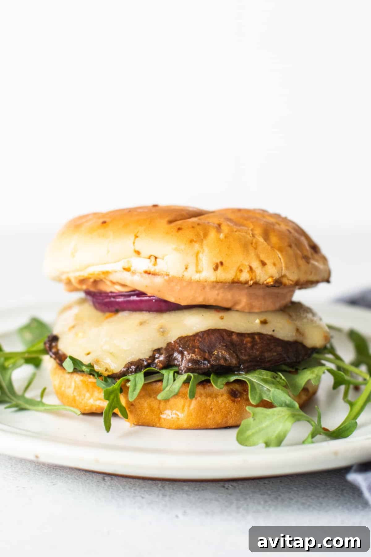 A vibrant and appealing portobello mushroom burger, showcasing its fresh toppings, melted cheese, and grilled patty, ready to be enjoyed.