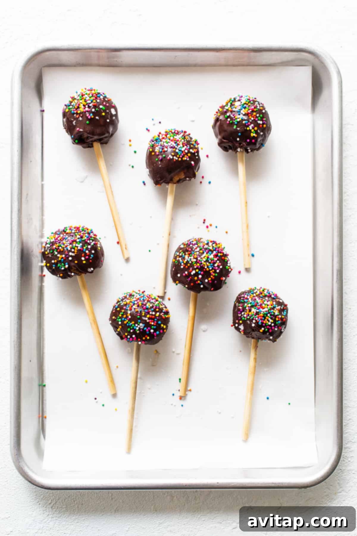 Several finished protein cake pops arranged on a parchment-lined cookie sheet, ready to be enjoyed.