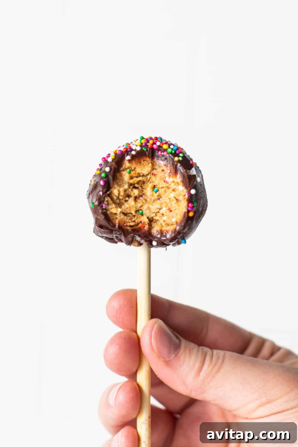 A protein cake pop with a bite taken out, revealing the cake-like interior.