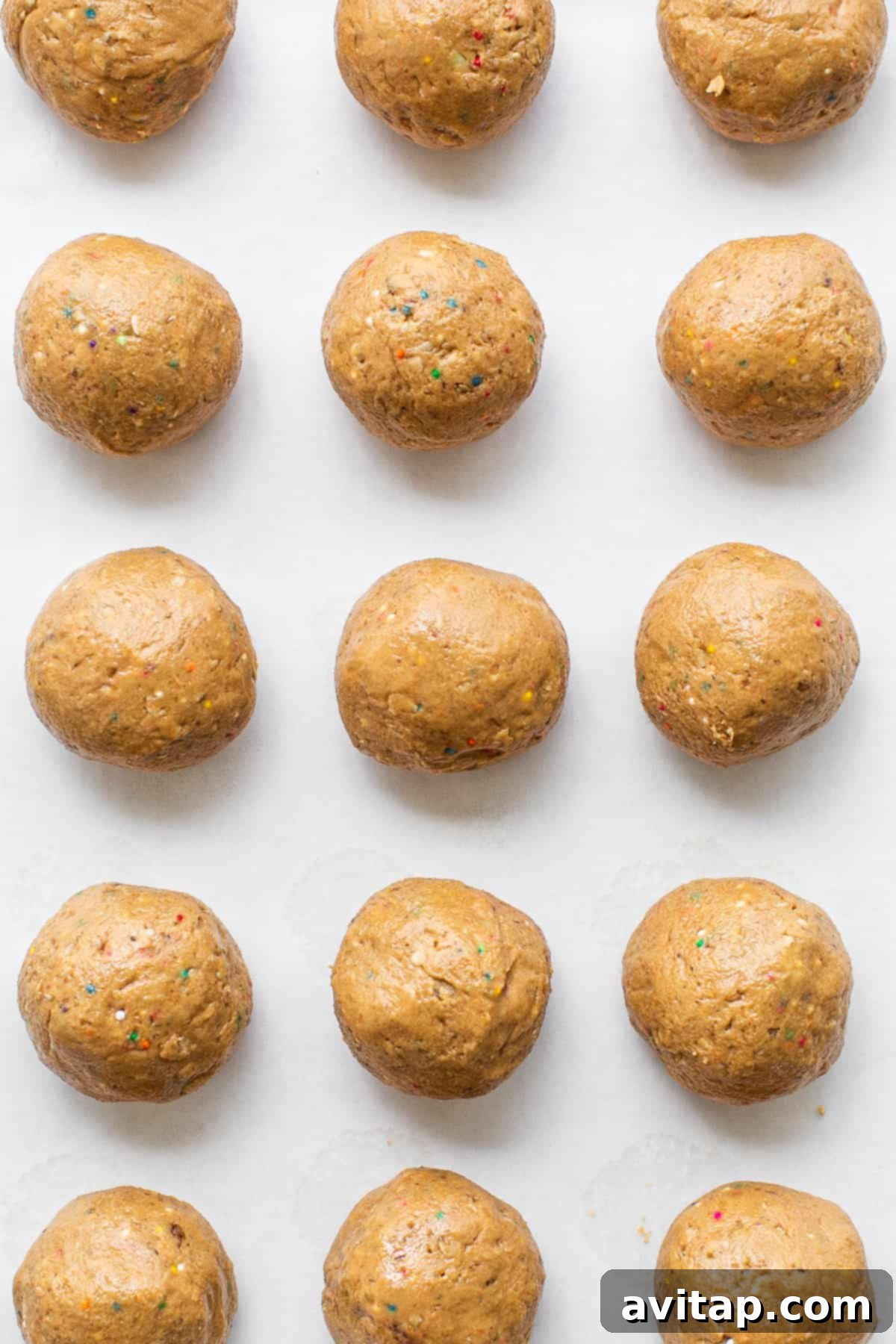 Rolled protein cake pop balls waiting to be coated on a parchment-lined cookie sheet.