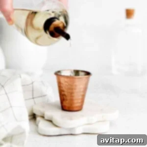 A small shot glass filled with clear, homemade simple syrup, ready to be used in cocktails or other recipes.