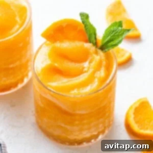 A vibrant Aperol Spritz slushy served in a glass, garnished with an orange slice, perfect for a refreshing summer drink.