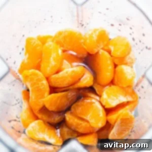 Frozen clementine slices being added to a blender for the Aperol Spritz slushy recipe.