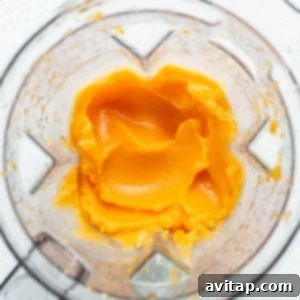 The blended frozen Aperol Spritz slushy is poured from the blender into a glass, ready for garnish.