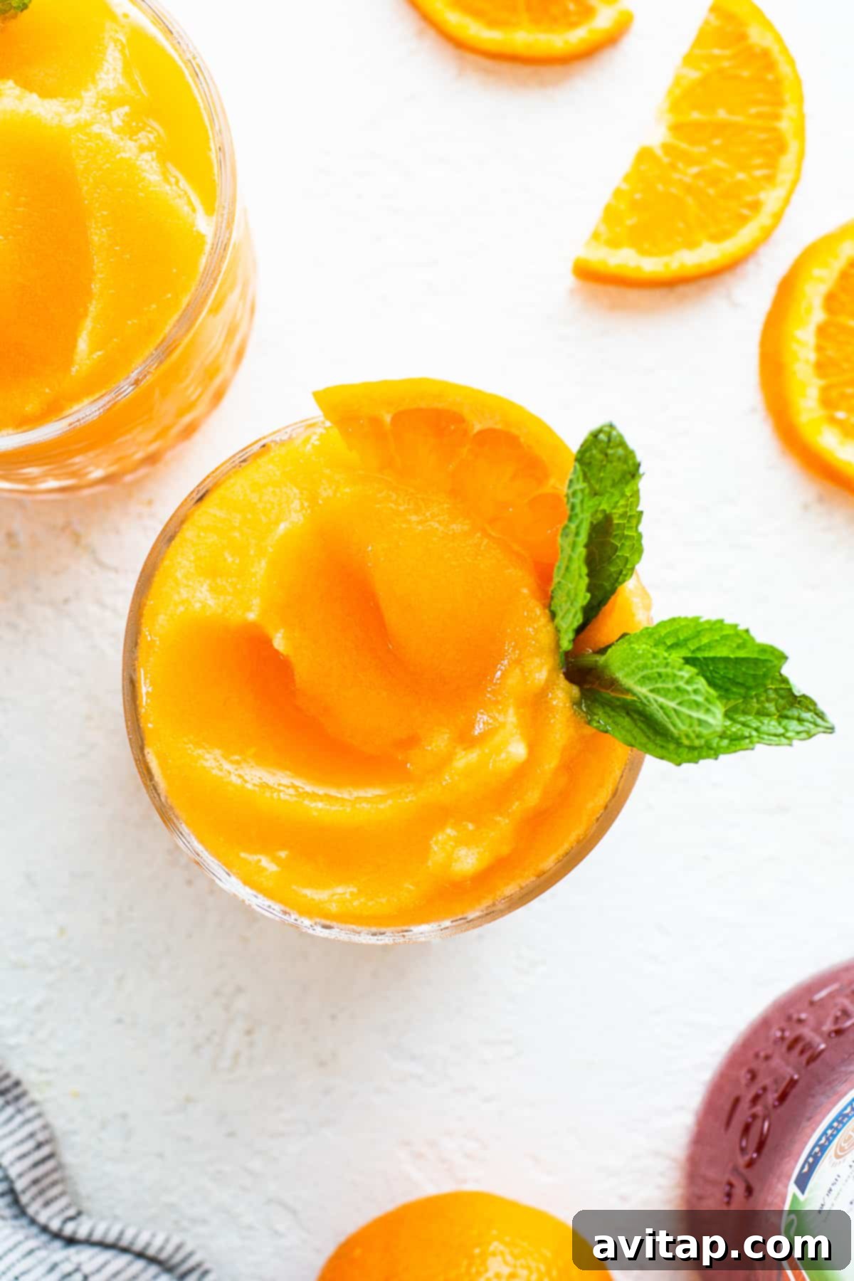 A beautifully presented Frozen Aperol Spritz Slushy in a tall glass, garnished with a fresh orange slice, glistening with condensation on a warm day.