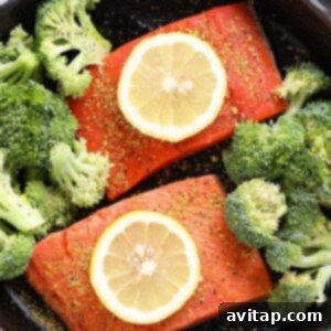 Lemon pepper salmon and broccoli in a pan with lemon slices, ready to bake.