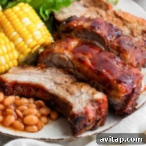 a plate of meat, beans, corn and corn on the cob.