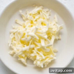 A white plate topped with shredded cold butter and honey mixed into dry ingredients.