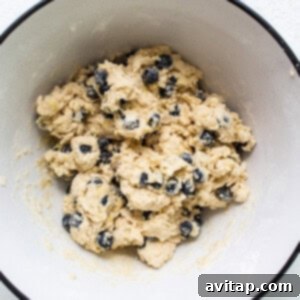 A white bowl filled with blueberry scone dough, showing its crumbly but cohesive texture.