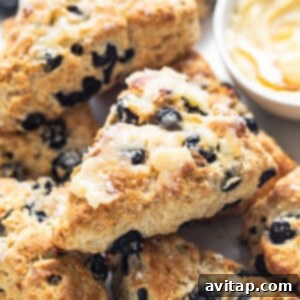 A white plate topped with freshly baked blueberry scones next to a small bowl of dip, just out of the oven.