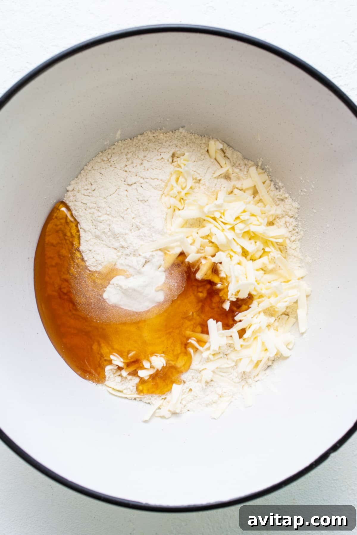 A white ceramic bowl holds a mixture of flour and other dry ingredients, ready for scone preparation.