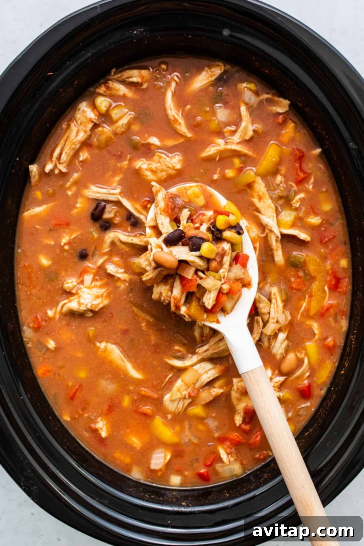 Close-up shot of chicken tortilla soup simmering in a slow cooker, showing the rich texture and vibrant colors of the ingredients.