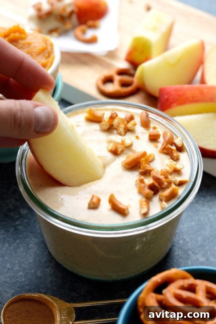 Spiced Pumpkin Yogurt Delight 2 A vibrant bowl of healthy pumpkin Greek yogurt dip, perfect for a snack or dessert. Served with apple slices and pretzels.