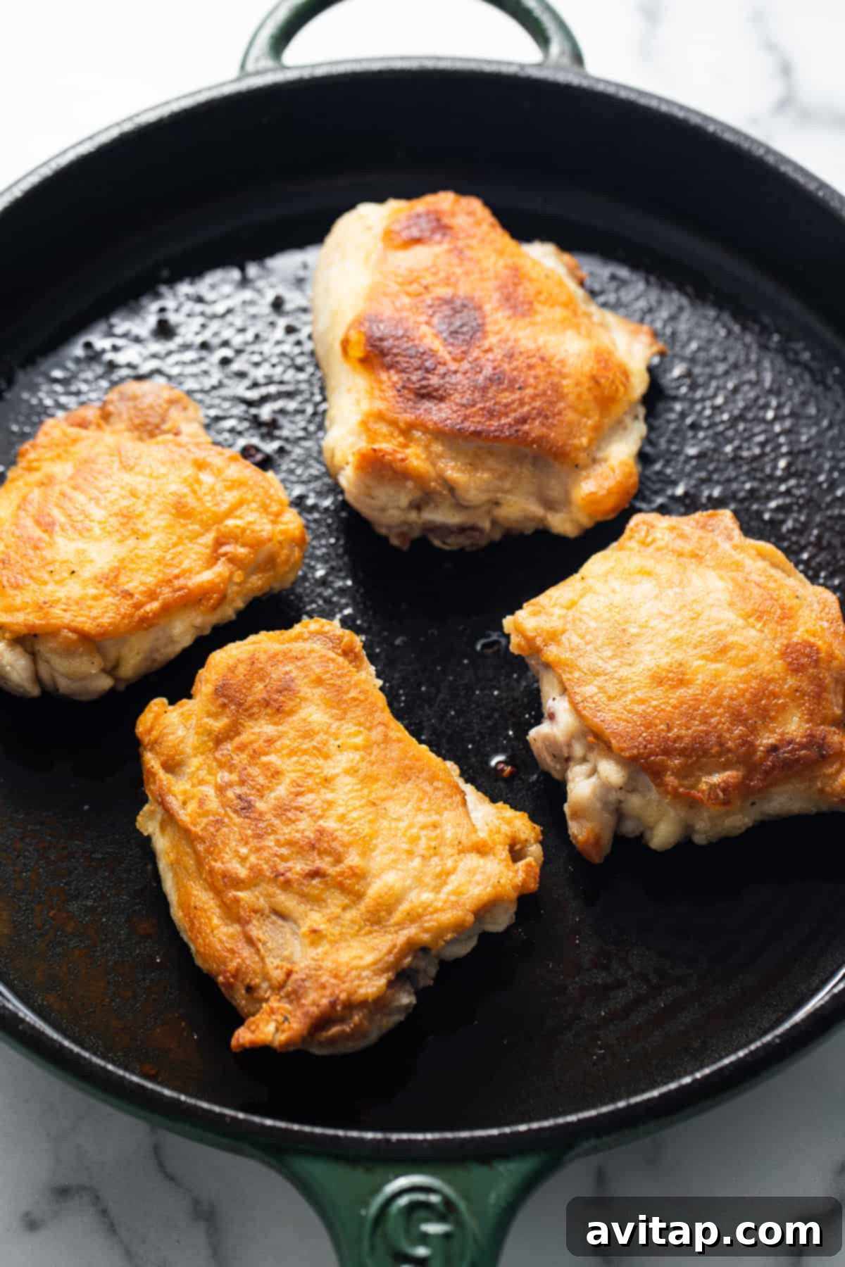 Close-up of chicken thighs searing beautifully in a cast iron skillet over high heat, creating a rich crust.