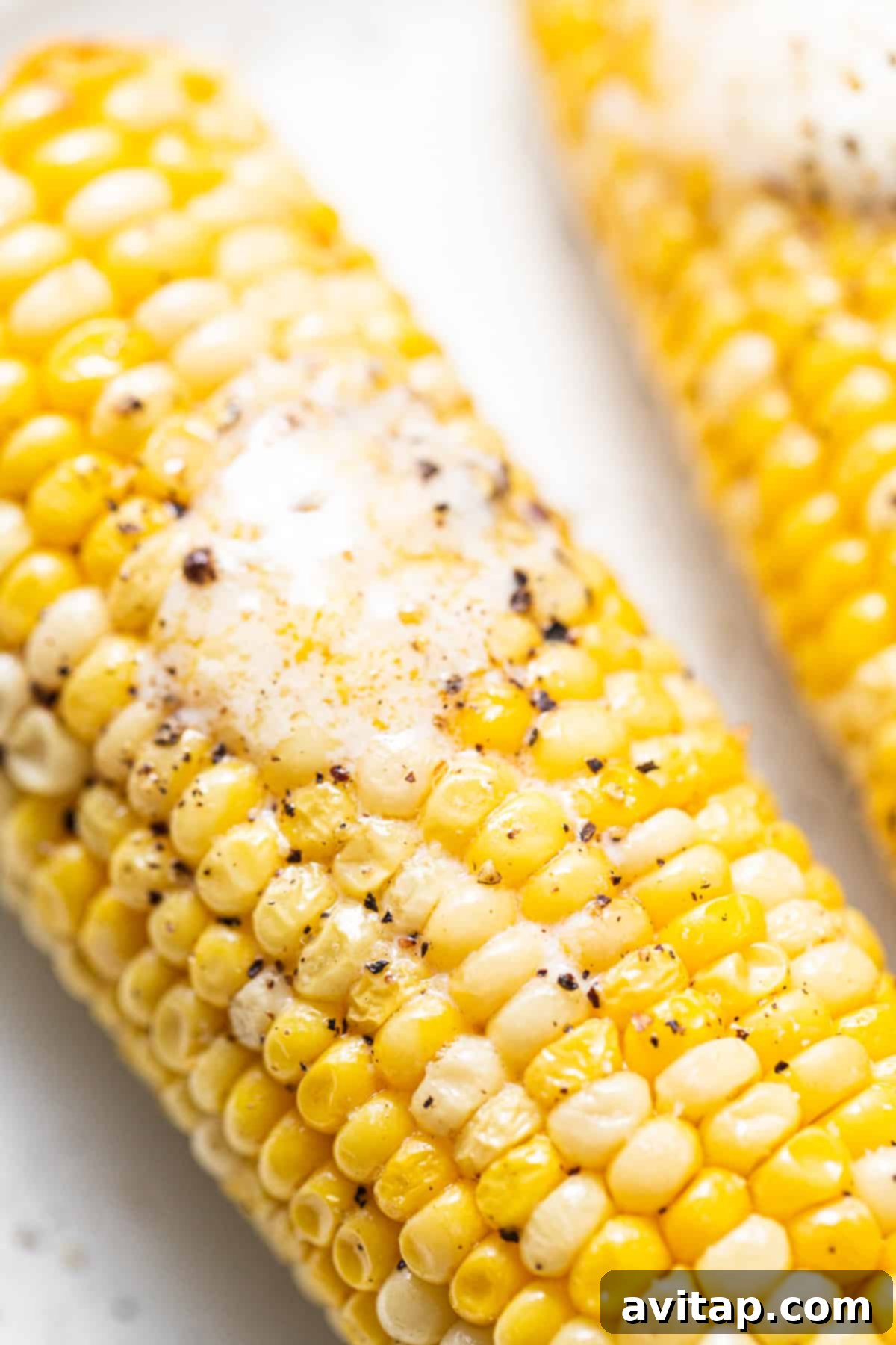 A close-up view of a single, perfectly cooked corn on the cob, showing its golden kernels.
