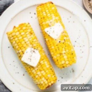 Two corn on the cob with butter on top, showcasing a golden finish.