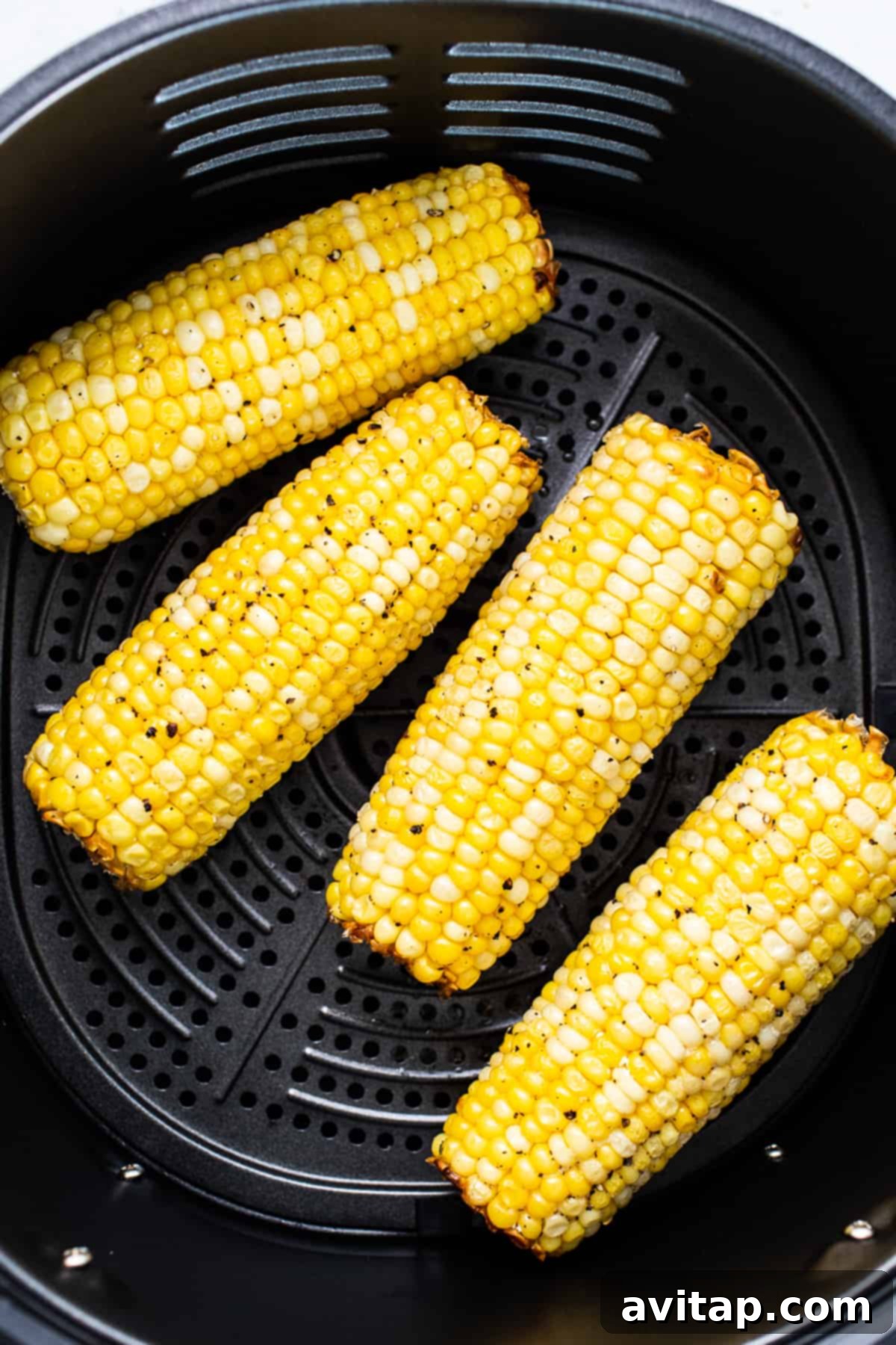 Corn on the cob placed in an air fryer basket, ready for cooking.
