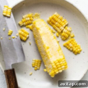 Corn on the cob on a plate with a knife.