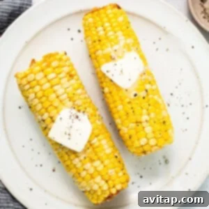 two corn on the cob with butter on top.
