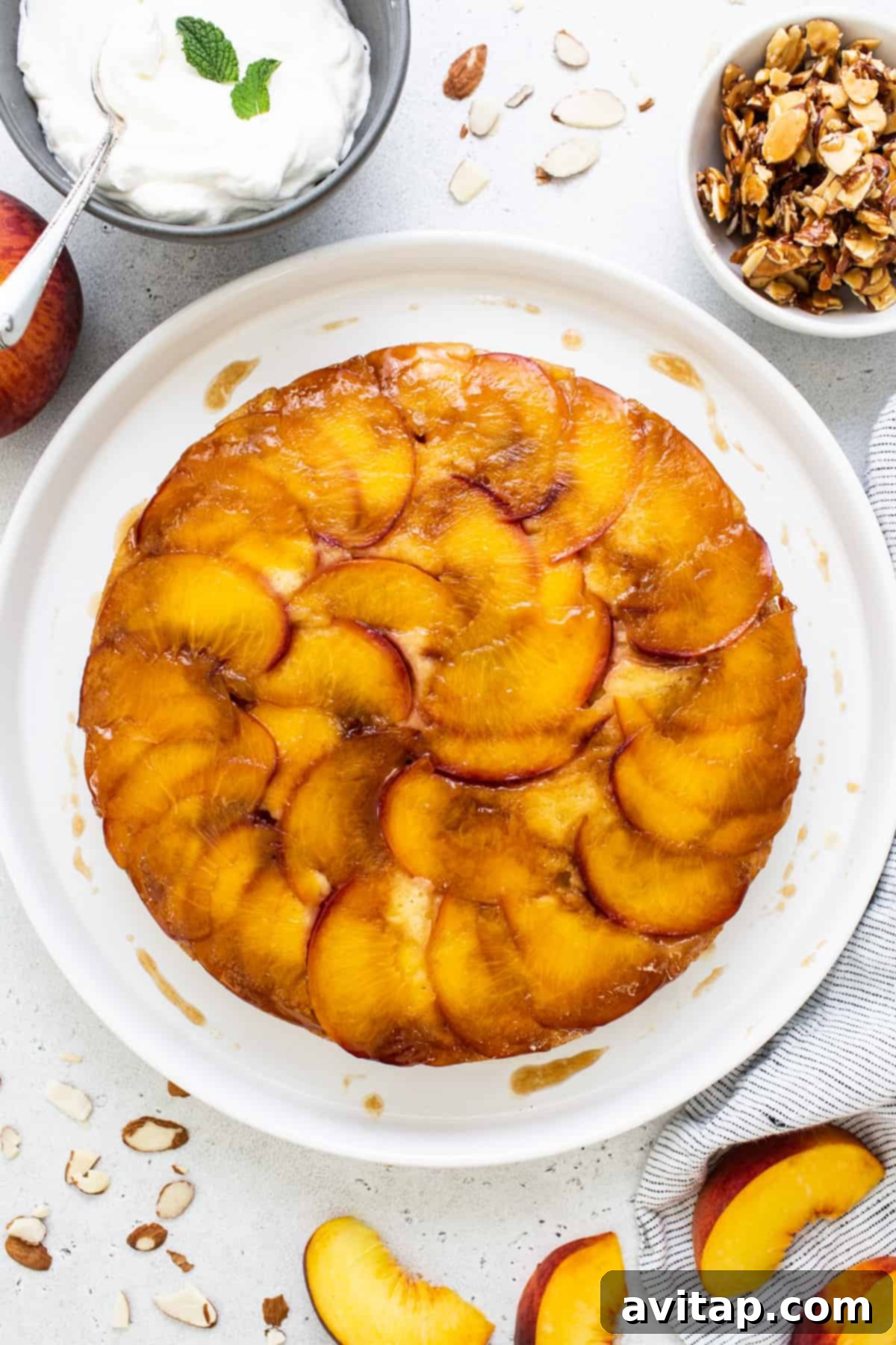 Golden Peach Upside Down Cake 5 A whole peach upside down cake artfully placed on a pristine white plate, adorned with a dusting of powdered sugar.
