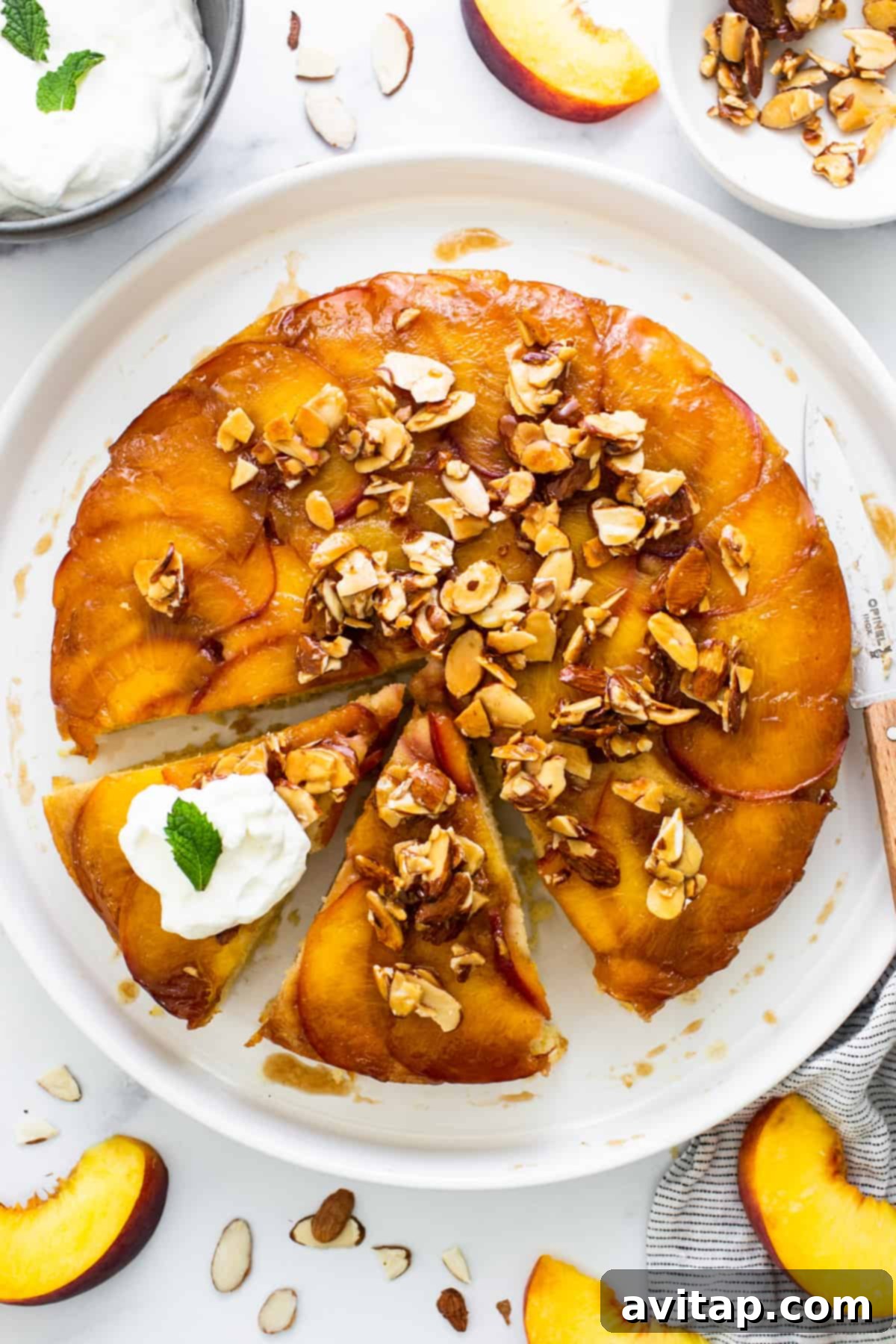 Golden Peach Upside Down Cake 6 A peach upside down cake on a white plate with a slice already taken out, revealing the moist interior.