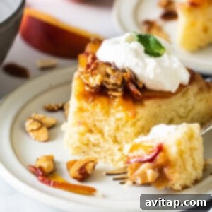 Golden Peach Upside Down Cake 8 A slice of peach cake with whipped cream and almonds on a plate.