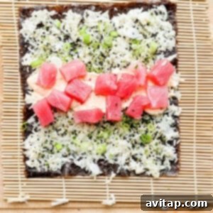 A piece of sushi being rolled on a bamboo mat, showcasing the technique to form a tight roll.