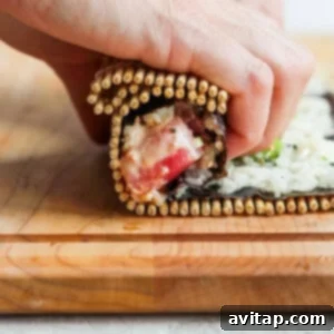 A person neatly arranging freshly rolled sushi logs on a wooden cutting board.