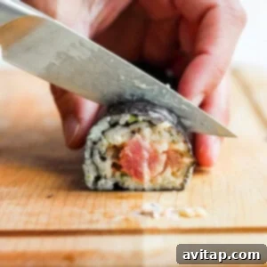 A person skillfully cutting a spicy tuna roll into perfect, bite-sized pieces with a sharp knife.