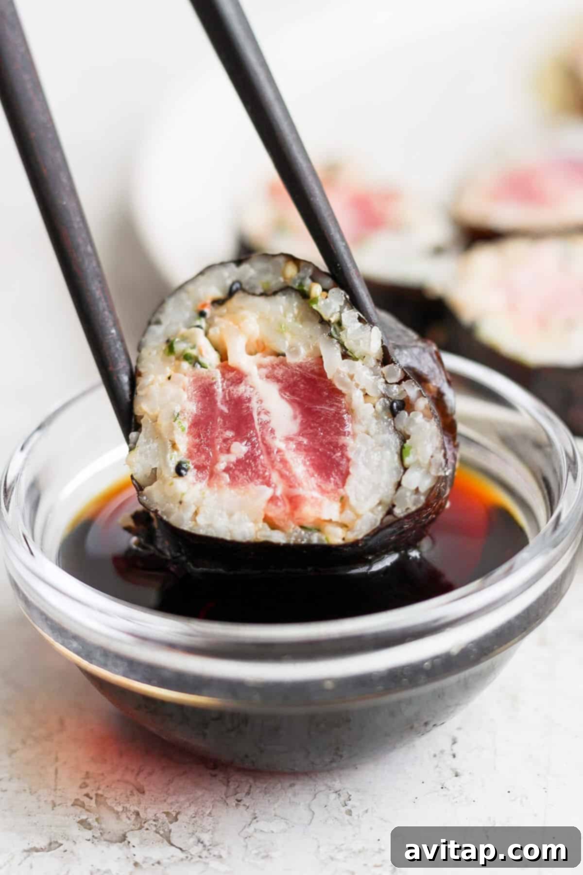 An appetizing close-up of Japanese tuna sushi in a bowl, accompanied by chopsticks.