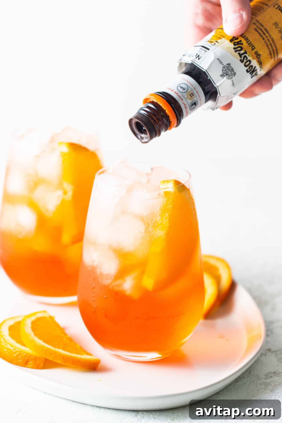 Bitters being poured in an aperol spritz.