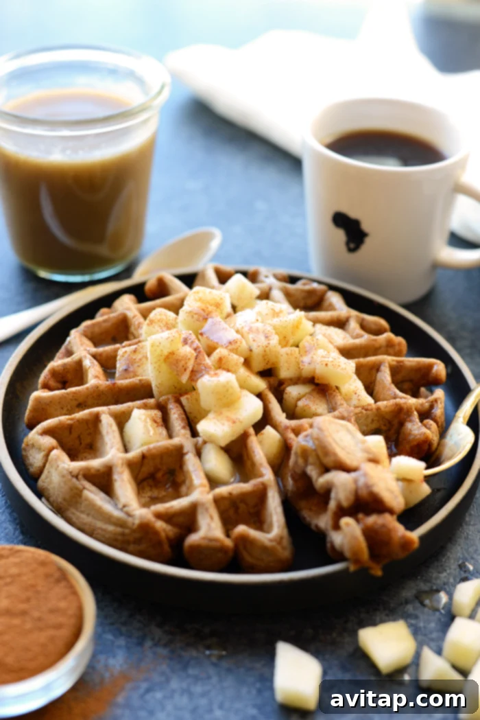Spiced Apple Cinnamon Waffles 2 A stack of golden brown apple cinnamon waffles topped with a rich homemade caramel sauce and fresh apple slices.
