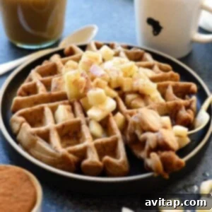 Apple cinnamon waffles on a plate with caramel sauce.