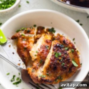 Perfectly Seared Cast Iron Chicken Thighs 13 A single piece of crispy chicken thigh on a white plate, garnished with chives and ready to eat.