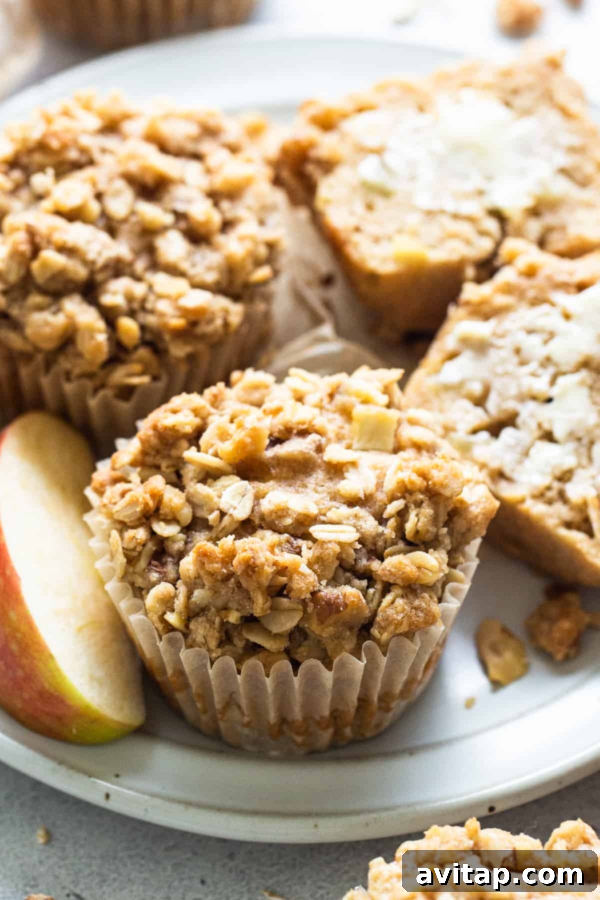 A plate of perfectly baked apple granola muffins, showcasing their golden-brown streusel topping and inviting texture.
