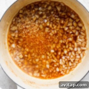 A pot with sauce and onions simmering.